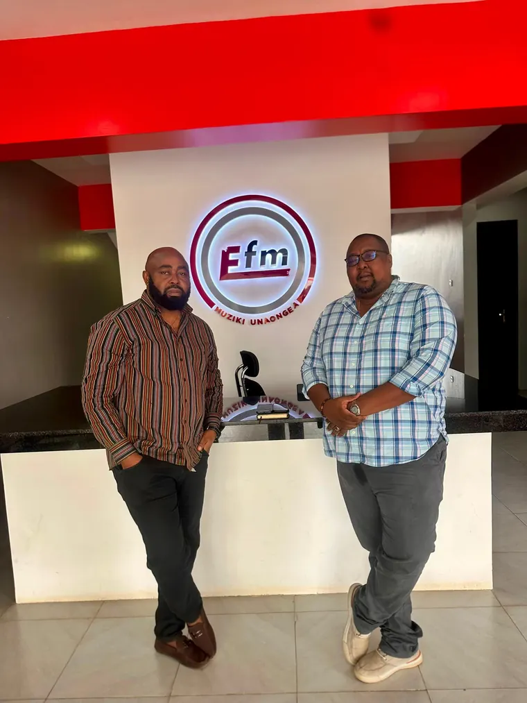 Stanley Msungu with a media partner beneath the EFM sign